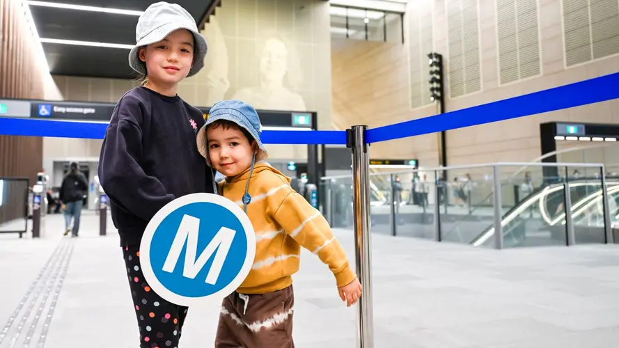 two kids holding the M logo at the City stations opening